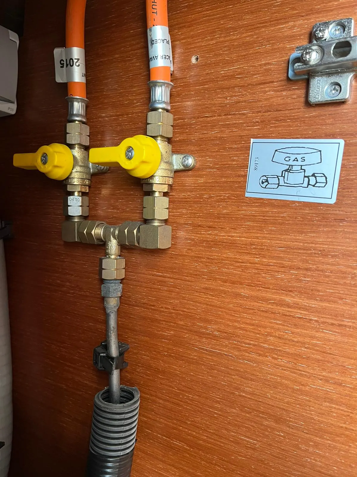 Zwei Absperrventile mit gelben Hebeln an einer Holzwand, daneben ein Aufkleber mit der Aufschrift GAS