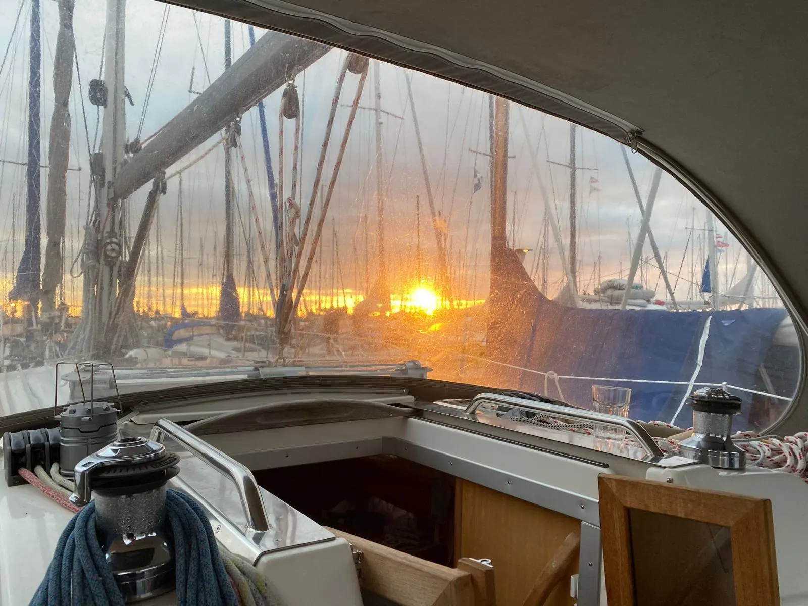 Sonnenuntergang über einer Marina, gesehen durch die Cockpitplane eines Segelboots